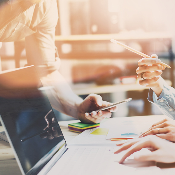 Team bespricht Marketingzahlen an Laptop und Smartphone